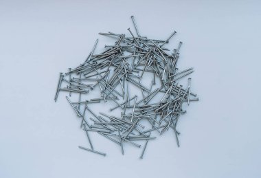 Orta boy çiviler gri arkaplanın ortasına saçılmış..