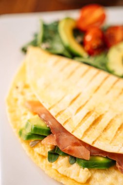 Beyaz tabakta salata ve somonlu tortilla..