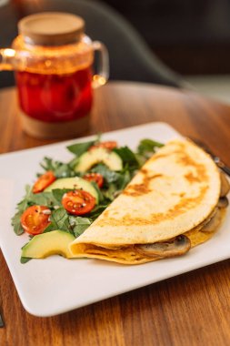 Kare beyaz tabakta salatalı tortilla..