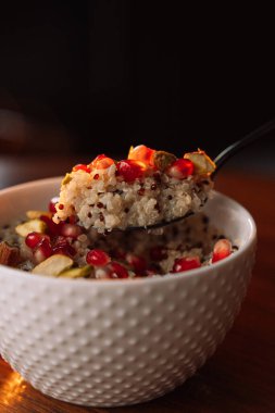 Nar ve fındıklı beyaz bir kâse içinde kinoa lapası..