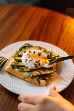 Ahşap zemin üzerinde haşlanmış yumurta avokadosu olan waffle..