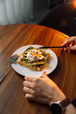 Ahşap zemin üzerinde haşlanmış yumurta avokadosu olan waffle..