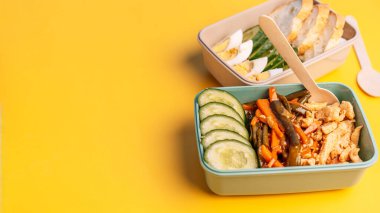 Parlak sarı arka planda ev yapımı sağlıklı yiyecekler ve tahta kaşıkla hazırlanmış iki plastik beslenme çantası. Yüksek kalite fotoğraf