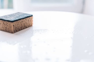 Beyaz bir masanın üzerindeki temiz bir süngerin parlak ve minimalist bir ortamda su damlacıkları ile yakın çekimi. Yüksek kalite fotoğraf