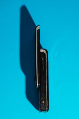 Retro kaydırmalı telefon, siyan kağıdının üzerinde dikey duruyor. Minimalist Y2K düzeni. Yüksek kalite fotoğraf