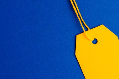 Close up yellow price tag on blue background with copy space. High quality photo
