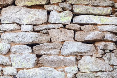 Close-up on a granite wall in need of repointing with lime mortar.