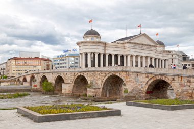 Skopje, North Mecedonia - May 21 2019: Stone Bridge opposite the the Archaeological Museum of Macedonia crossing the Vardar River.