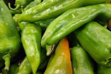 Close-up on a stack of green ox horn peppers on a market stall.