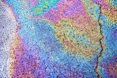 Full frame close-up on Gasoline all over a wet pavement.