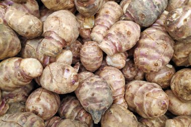 Close-up on a stack of Jerusalem artichokes for sale on a market stall.