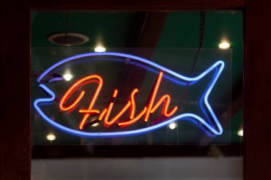 Blue neon light shaped into a fish a red neon inside it shaped into the word : Fish.