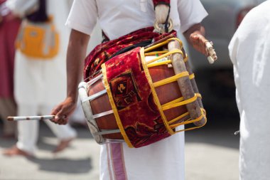 Close-up on a musician playing with a Thavil during a Tamil procession.