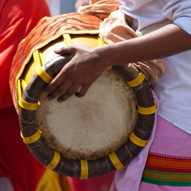 Close-up on a musician playing with a Thavil during a Tamil procession.