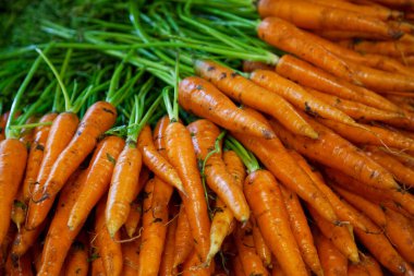 Full frame close-up on a stack of carrots on a market stall.