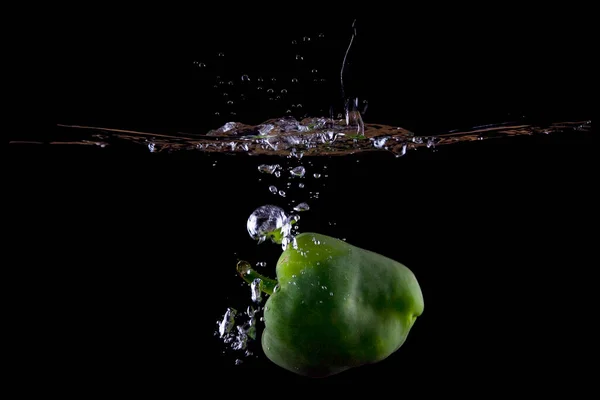 Green bell pepper water splash on black background showing water level.