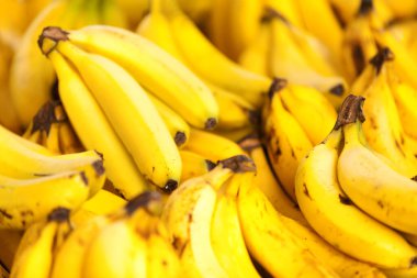 Close-up on a stack of yellow bananas on a market stall.