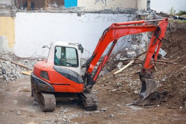 Red and white mini excavator on a construction site.