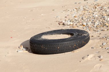 Tire released by the tide polluting the beach.