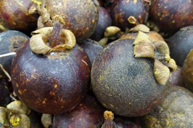 Close-up on a stack of mangosteens for sale on a market stall.