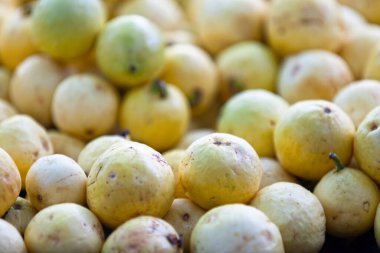Full frame close-up on a stack yellow guavas on a market stall.