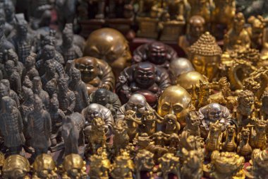 Various chinese statuettes for sale on a market stall.