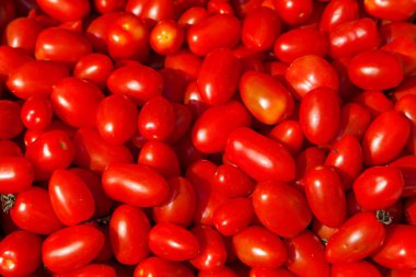 Close-up on a stack of red plum tomatoes for sale on a market stall.