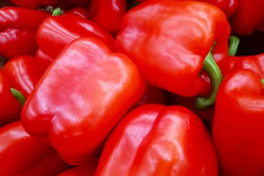 Close-up on a stack of red bell peppers on a market stall.