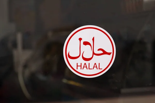Circular sign in a window with written in arabic, meaning Halal.