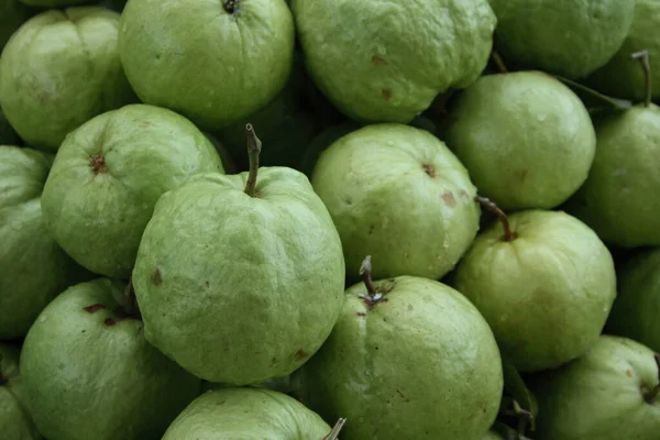 Close-up on a stack of guava apples for sale on a market stall.