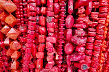 Close-up on a stack of necklaces made of red corals in a market stall.