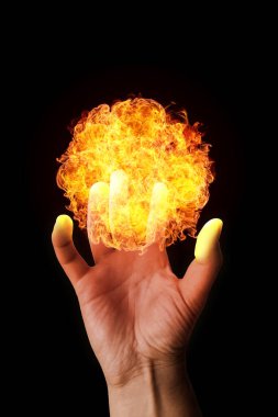 Close-up on a man's hand holding a fireball isolated on a black background.