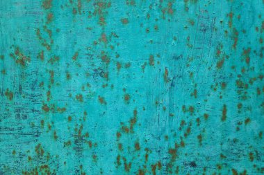 Full frame close-up on a rusty metal plate painted in turquoise.