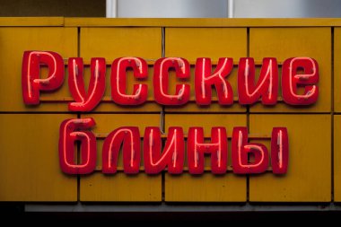 Close-up on a red neon light shaped into the Russian short phrase meaning 