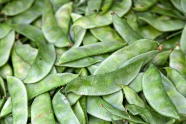 Close-up on a stack of Avaraikai (Broad Beans) on a market stall.