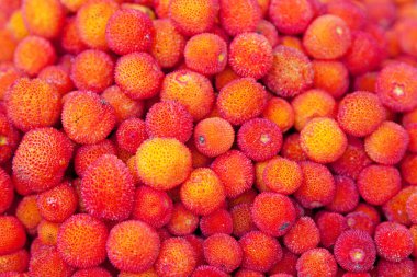 Close-up on a stack of Arbutus berries for sale on a market stall.
