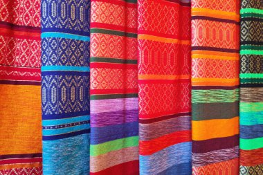 Close-up on a stack of colorful scarves made on a market stall.