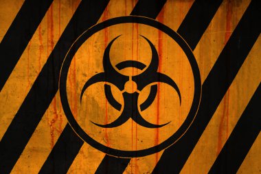 Full-frame weathered concrete wall covered with rust stains and paint in yellow and black stripe with a biohazard symbol.