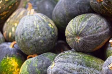 Full frame close up on a stack of pumpkins (Cucurbita maxima Duchesne) on a market stall.