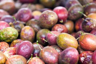 Close-up on a stack of passion fruits for sale on a market stall.