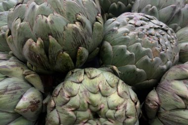 Close-up on a stack of artichokes for sale on a market stall.