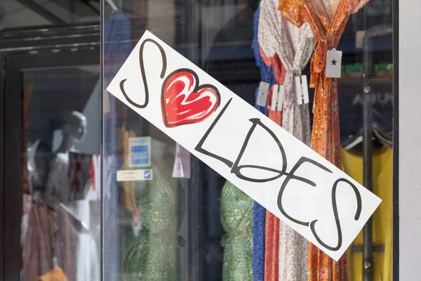 White sign in a window shop saying in French Soldes, meaning in English Sales.