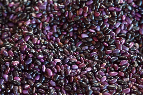 Full frame close-up on a stack of black beans on a market stall.