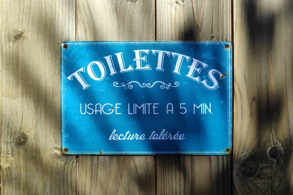 Blue laminated metal plate with a humorous text stating in French \