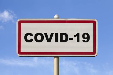 Bir Fransız, şehir tabelasının ortasında COVID-19 yazılı mavi gökyüzü ile karşılaşır..