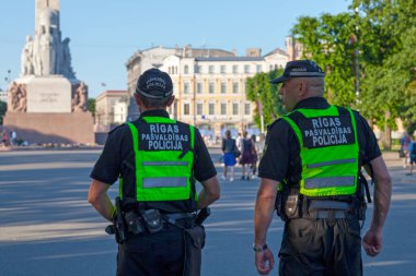Riga, Letonya - 14 Haziran 2019: Riga Belediye Polisi 'nden iki memur Özgürlük Anıtı yakınlarındaki meydanda devriye geziyor.