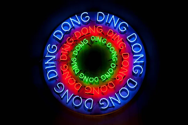 Close-up on a colorful circular sign composed of colorful neon light shaped into the words \