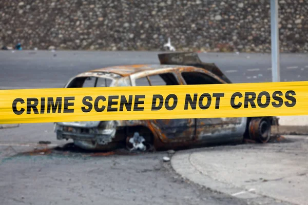Car burnt by a pyromaniac with a police tape with written in it in 