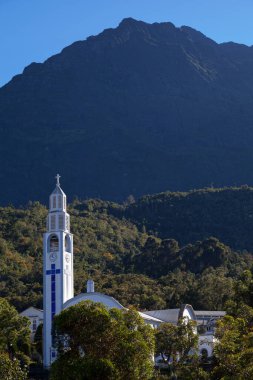 Church of Notre Dame des Neiges in Cilaos (Reunion Island) with the Piton des Neiges in the background. clipart