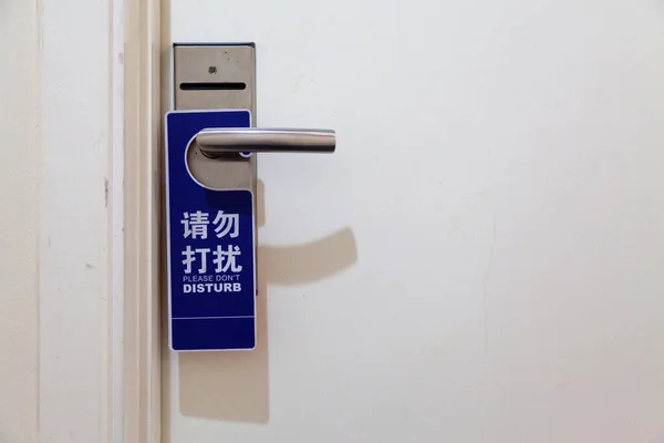 ホテルの部屋のハンドルからぶら下がっている中国語と英語で 邪魔しないでください の看板 — ストック写真